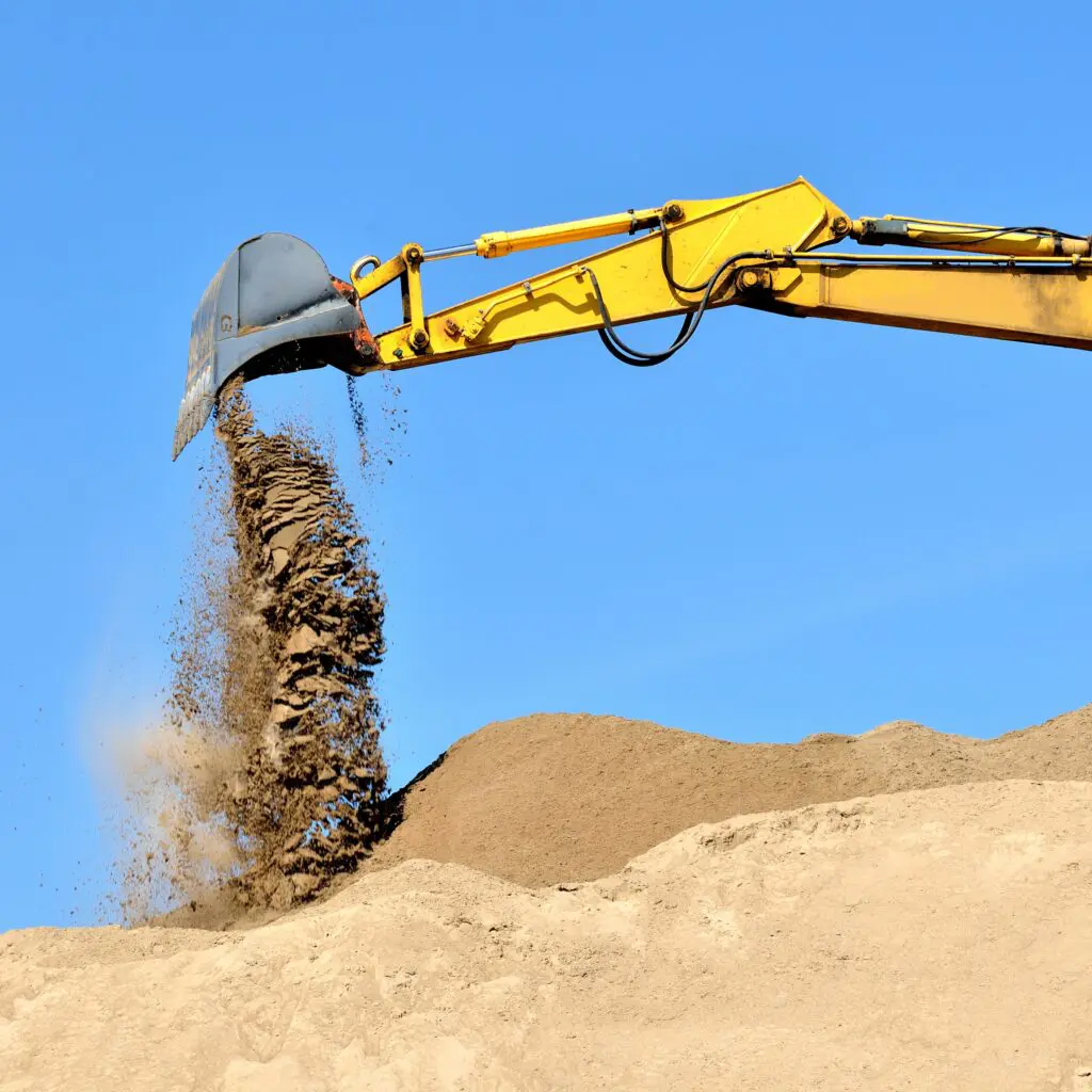 Excavator dumping sand on pile