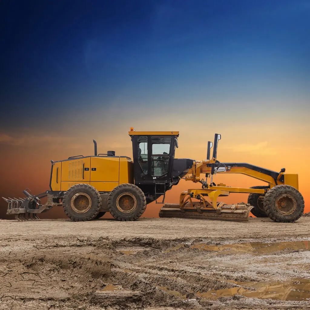 Heavy machinery on dirt ground, sunset background
