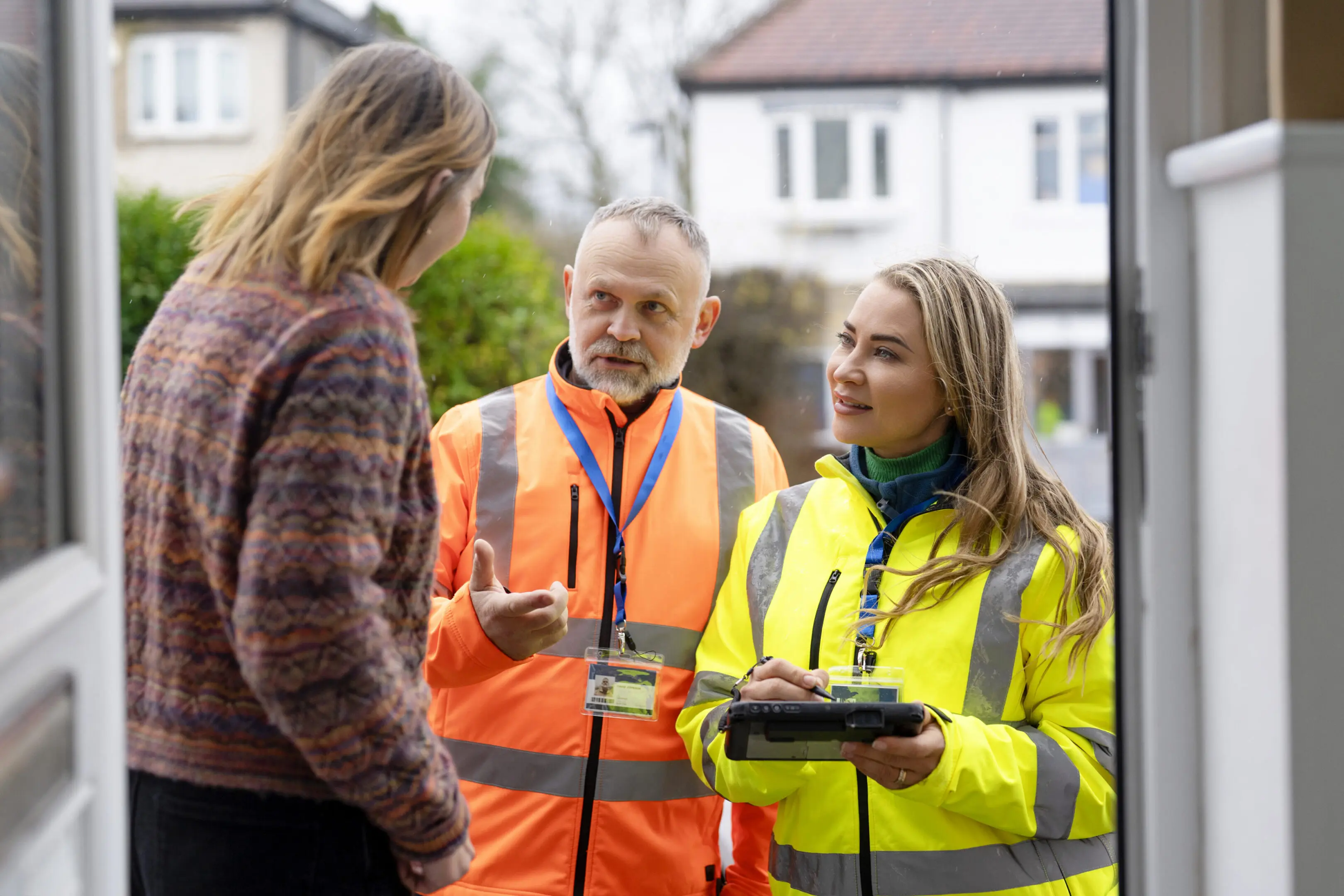 Workers and resident talking outside a house