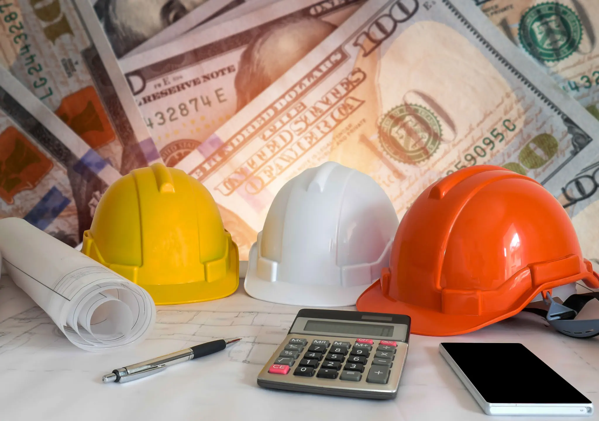 Hard hats, blueprints, and calculator on table