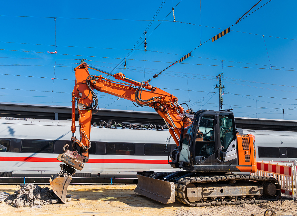 Orange excavator beside moving train