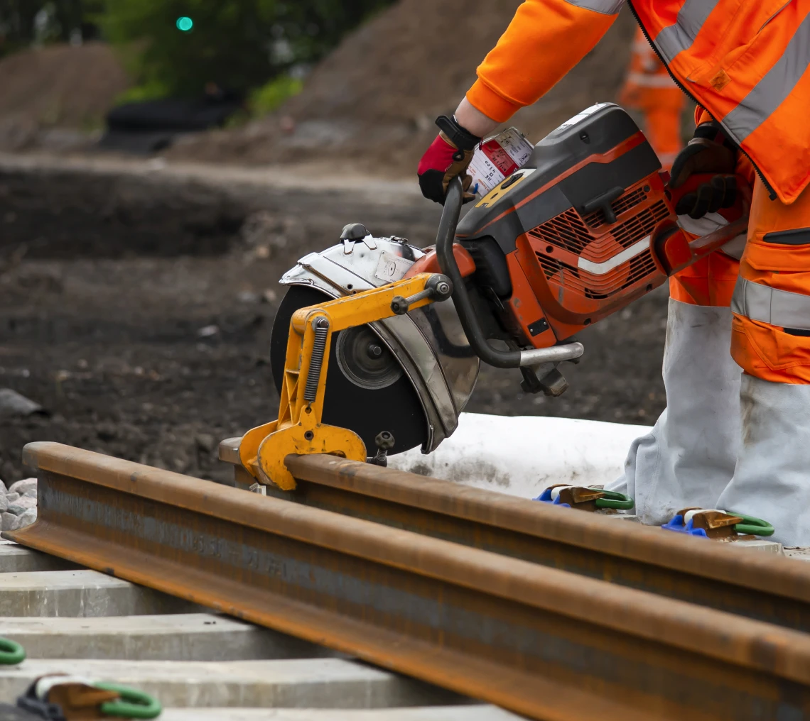 Worker cutting rail with power saw